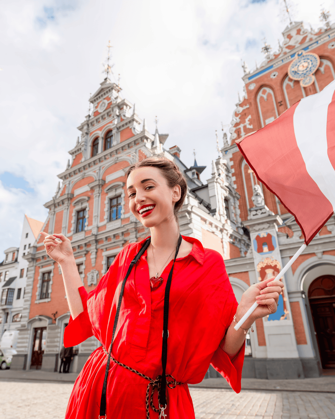 Woman in red dress holding flag of latvia in riga